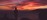 Silhouette of a figure on a coastal cliff at dawn - dramatic sunrise over the sea