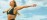 Monika Bal arms outstretched, face lifted, smiling in open air against a bright sky